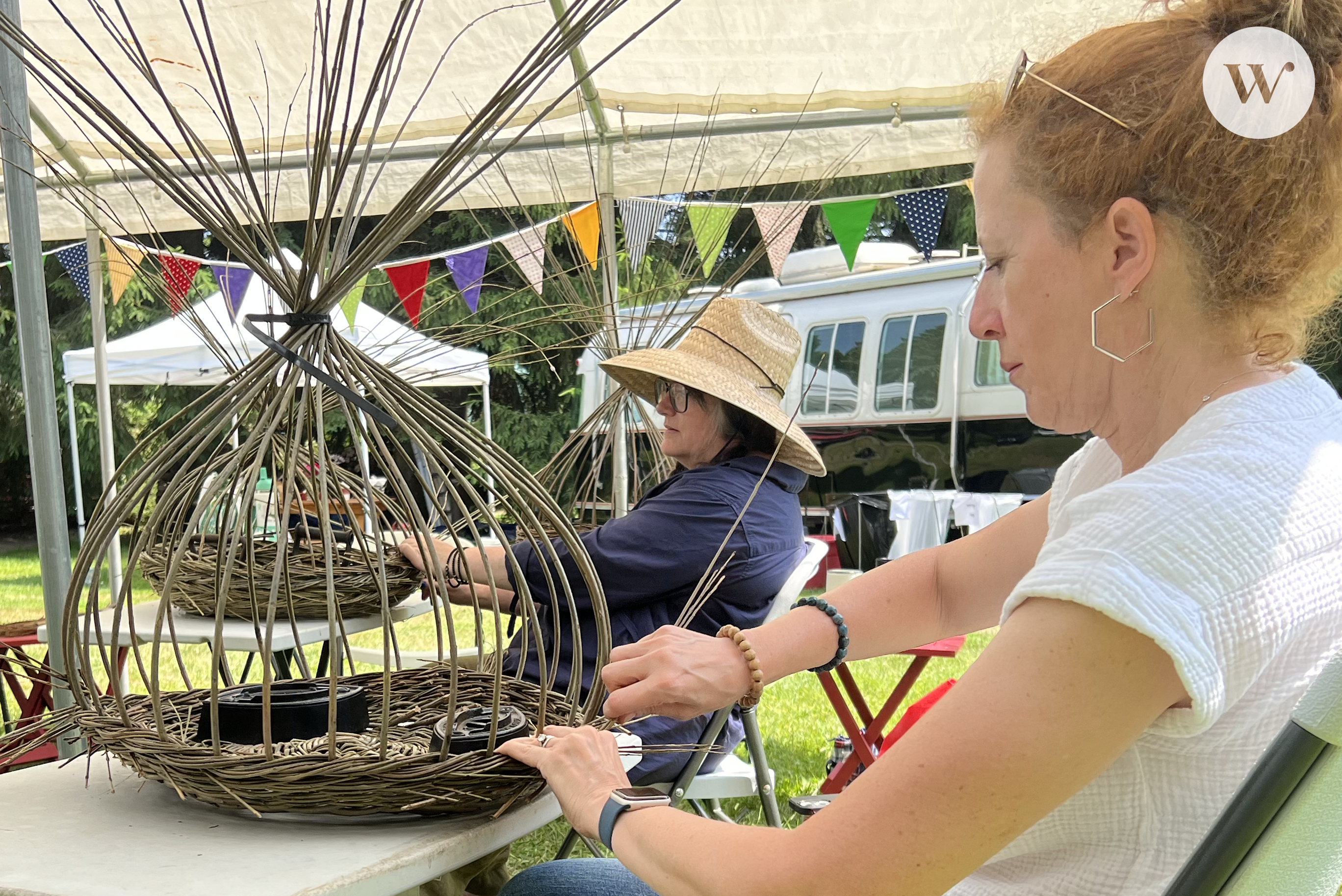 A photograph of some willow weaving class participants. They are focused on creating various sculptures and bowls or baskets.
